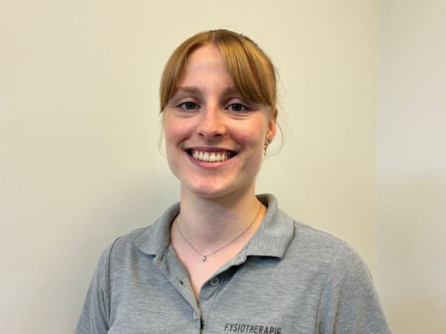 Teamlid van Fysiotherapie De Dijken in een grijze polo met het praktijklogo.