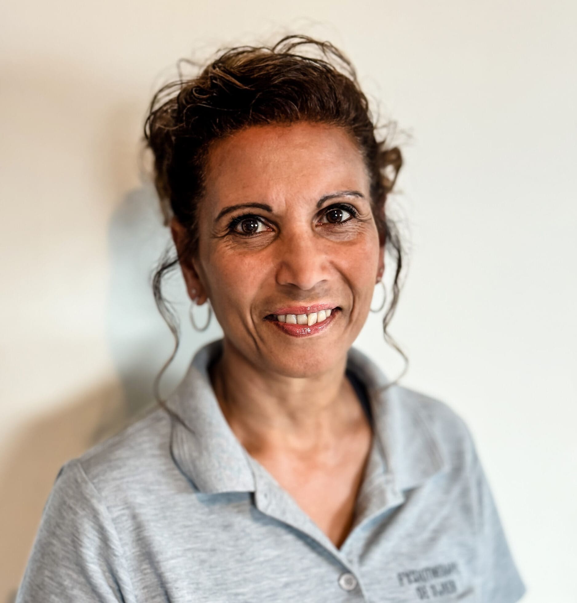 Teamlid van Fysiotherapie De Dijken, portret tegen een lichte wand.